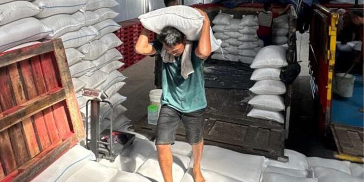 Pekerja memanggul beras di gudang Bulog